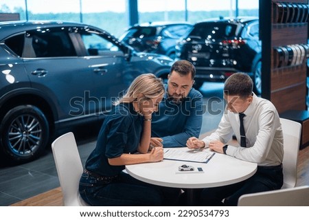 Happy caucasian couple signs a contract for the purchase of a car salon. Royalty-Free Stock Photo #2290534793