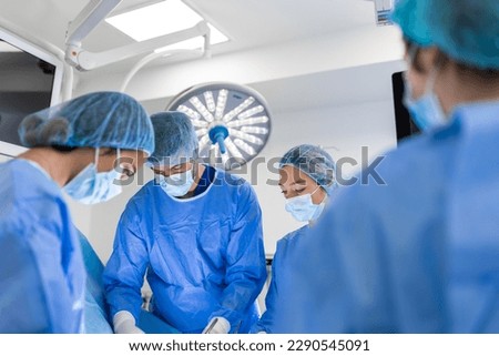 Team of Professional surgeon, Assistants and Nurses Performing Invasive Surgery on a Patient in the Hospital Operating Room. Surgeons Talk and Use Instruments. Real Modern Hospital.