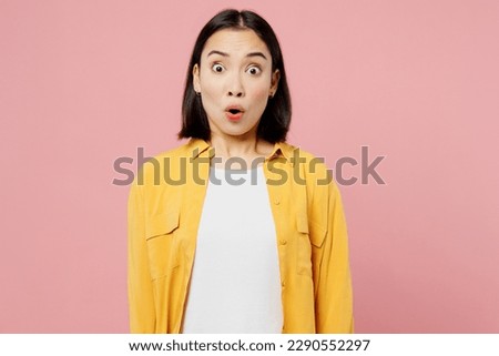 Young sad astonished shocked surprised woman of Asian ethnicity wear yellow shirt white t-shirt looking camera isolated on plain pastel light pink color background studio portrait. Lifestyle concept Royalty-Free Stock Photo #2290552297