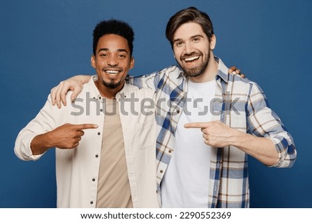 Young two friends fun cool men wear white casual shirts together looking camera put hand on shoulder point finger on each other isolated plain dark royal navy blue background. People lifestyle concept Royalty-Free Stock Photo #2290552369