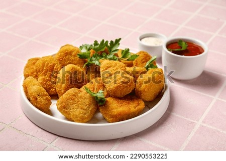Plate of tasty nuggets on pink tile background Royalty-Free Stock Photo #2290553225