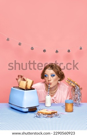 Beautiful young girl with bright makeup drinking milk, eating toast with confetti over pink studio background. Party and celebration. Food pop art photography. Concept of retro style, creative vision