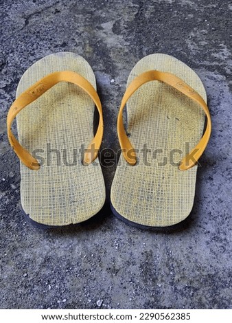 East Java, Indonesia - 18, April 2023. Yellow flip flops on a concrete background.  Royalty-Free Stock Photo #2290562385
