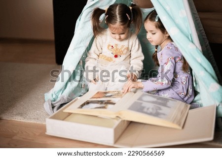 Two girls sisters at wigwam tent looking at parents wedding album.