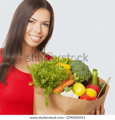 Square image of cheerful smiling woman in casual cloth wear, red sweater hold grocery shopping bag with vegetarian raw food vegetables, isolated over light grey gray background. Healthy eating dieting