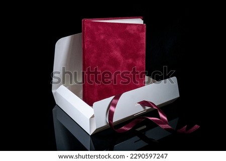 Best gift for men. Man gift concept. Red notebook with open white gift box on black background. Copy space text. Valentine's day, wedding, birthday and special occasion gift concept. Copy space.