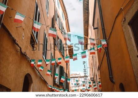 Italian flags and pennants in an old town narrow street of a city in Pisa, Italy. High quality photo
