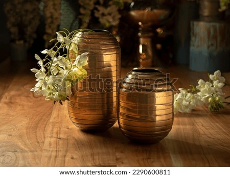 Beautiful gold vases, with artificial flowers, on a wooden table, household items, retro Royalty-Free Stock Photo #2290600811