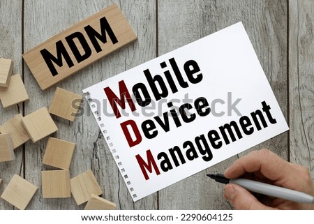 Text MDM - Mobile Device management text on torn page near wooden cubes