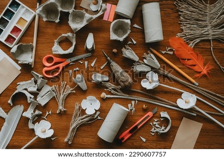 Handmade flowers from egg carton on wooden table with tools. Creative DIY idea for kids as gift for birthday, valentine, Easter, mothers day. Eco friendly zero waste simple craft. Messy desk flat lay. Royalty-Free Stock Photo #2290607757