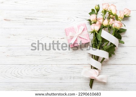 design concept with pink rose flower and gift box on colored table background top view. Happy Holiday, Mothers day, birthday concept. Romantic flat lay composition.