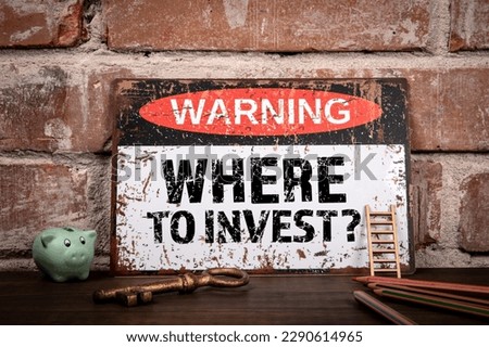 Where to invest. Warning sign with text on wooden office desk.