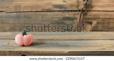 small crochet pink pumpkin on wooden background, space for text and advertisements
