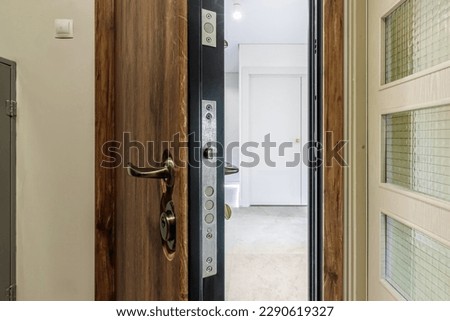 Entrance wooden door of natural color, in a multi-storey building. Entrance to the apartment.