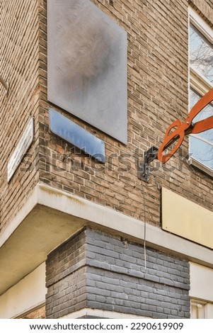 an orange crane hanging from the side of a brick building in front of a window with a sign on it