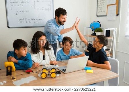 Excited teacher and teen student doing a high five celebrating finishing an electronic robotic project  Royalty-Free Stock Photo #2290623221