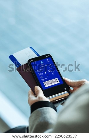 Passenger holding smartphone checking travel information on electronic boarding pass before flying. Traveler using digital boarding pass for air travel. Royalty-Free Stock Photo #2290623559