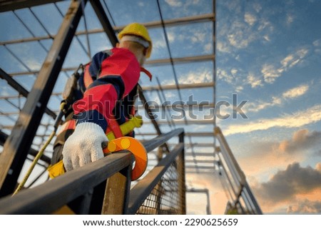 Asian male construction worker working at height on steel frame Wear safety gear and safety harness to work at high heights at the construction site. Royalty-Free Stock Photo #2290625659