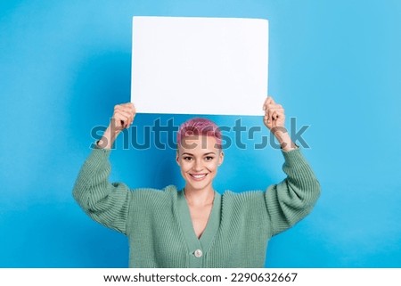 Photo of cheerful gorgeous lady wear trendy clothes hold white banner sale discount empty space isolated on blue color background