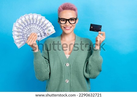 Photo of positive candid lady wear trendy clothes earn money hold plastic card banknotes isolated on blue color background