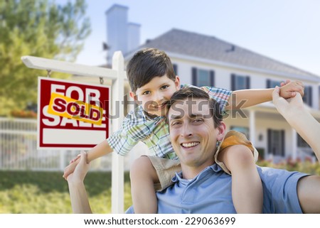 Mixed Race Father and Son Celebrating with a Piggyback in Front of House and Sold Real Estate Sign.