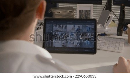 Security officer monitors CCTV cameras in coworking office on digital tablet computer. Modern program showing footage of surveillance cameras on screen. High tech security. Concept of social safety. Royalty-Free Stock Photo #2290650033