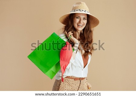 Beach vacation. happy stylish housewife in white blouse and shorts on beige background with bikini and summer hat.