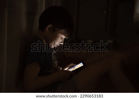 Kid who plays games on the internet at night. Portrait of a teenager boy using mobile phone on dark room. Bad habits of teenagers. Boy addicted with phone Royalty-Free Stock Photo #2290653183