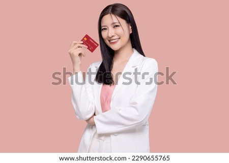 Beautiful young Asian business woman wearing white suit smiling, showing, presenting credit card for online payment isolated on pink background.