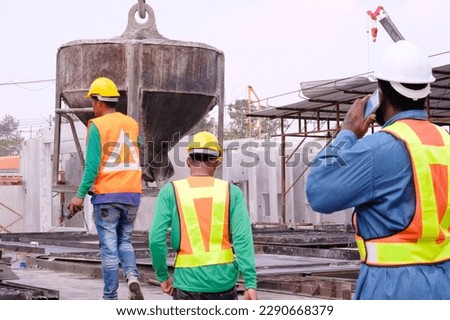 Engineers and workers pouring cement at construction site.