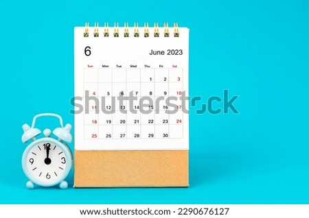 June 2023 Monthly desk calendar for 2023 year and alarm clock on blue background. Royalty-Free Stock Photo #2290676127