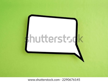 White speech bubble shaped post it note on green background with copy space.
