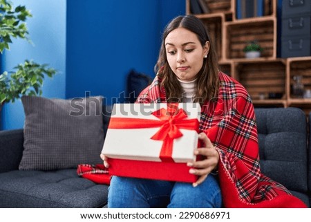 Young hispanic woman opening gift box skeptic and nervous, frowning upset because of problem. negative person. 