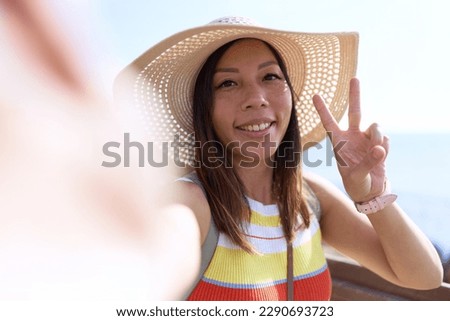 Young asian woman tourist making selfie by the camera at seaside