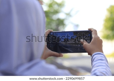 Rear view of a girl taking a picture with a smartphone about the scenery
