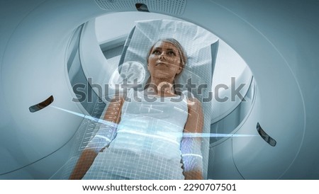 Female Patient Lying on a CT or PET or MRI Scan, Moving Inside the Machine While it Scans Her Brain and Vital Parameters. AR Concept of Visual Effects In Medical Lab with High-Tech Equipment. Royalty-Free Stock Photo #2290707501