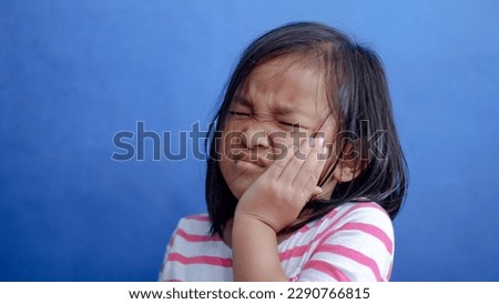 Asian kid girl toothache. Kid suffering from toothache. Asian child hand on cheek face as suffering from facial pain, mumps toothache. Dental health care. Royalty-Free Stock Photo #2290766815