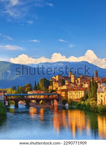Bridge Ponte Degli Alpini at River Brenta Bassano Del Grappa Italy. Panoramic View Old Town with Vintage Building and Tower Wooden Background Alpine Mountains Scenic Landscape Evening Sunset Royalty-Free Stock Photo #2290771909
