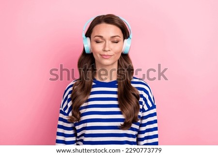 Photo of positive peaceful cute woman with wavy hairdo dressed striped shirt enjoy favorite playlist isolated on pink color background