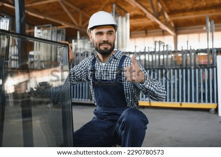 The glazier carries the glass in the glass factory Royalty-Free Stock Photo #2290780573