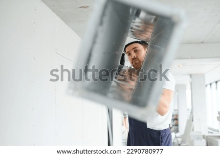 Industrial Theme. Warehouse Heating and Cooling System Installation by Professional Caucasian Technician. Commercial Building Ventilation Rectangle Canals. Air Distribution Royalty-Free Stock Photo #2290780977