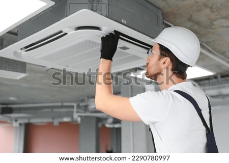 Happy Male Technician Repairing Air Conditioner. Royalty-Free Stock Photo #2290780997