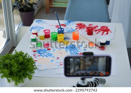 Children bloggers are streaming finger painting. live broadcast, online. Kids have fun and create picture. Palms of different colors. Sensory development and experiences