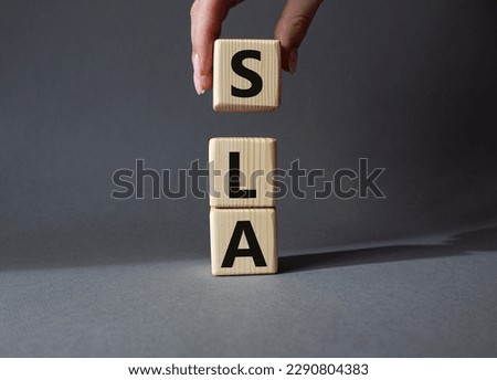 SLA - Service Level Agreement. Wooden cubes with word SLA. Businessman hand. Beautiful grey background. Business and Service Level Agreement concept. Copy space.
