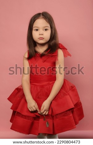 cute little girl in red dress happy close up portrait on pink background