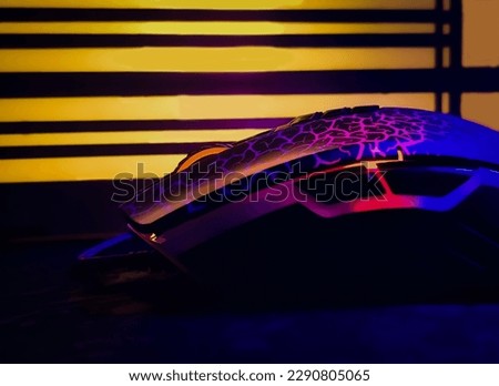 Modern colorful RGB Gaming mouse in front of a glowing light from silhouette table lamp 