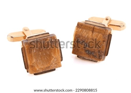 A pair of yellow gold cufflinks set with a square tiger eye gem stone. Isolated on white.