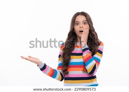 Look at advert. Teenager child points aside shows blank copy space for text promo idea presentation, poses against white isolated background. Surprised face, surprise emotions of teenager girl. Royalty-Free Stock Photo #2290809573