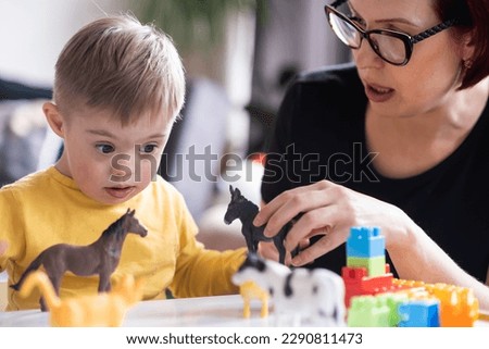  child with Down syndrome exploring their creativity and learning with colorful geometric shapes, supported by their family in a relaxed and enjoyable activity at home Royalty-Free Stock Photo #2290811473