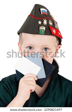 Eighteen 18 precent grey gray card, white and black card used for photography with young caucasian boy in Russian military hat in background